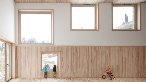 Heller Raum mit Holzverkleidung an der Wand, mehreren quadratischen Fenstern und einem Kind auf einem Laufrad