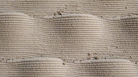 Detailaufnahme der geschichteten Oberfläche einer 3D-gedruckten Lehmwand mit sichtbaren horizontalen Druckschichten und natürlicher Materialtextur.