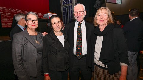 Vier Teilnehmende posieren lächelnd für ein Foto vor der Bühnenkulisse des „Jahresempfangs der Wirtschaft“.