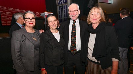 Vier Teilnehmende posieren lächelnd für ein Foto vor der Bühnenkulisse des „Jahresempfangs der Wirtschaft“.