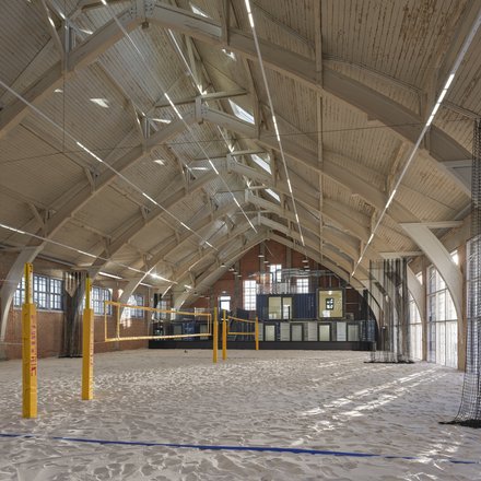 Sandhalle mit Volleyballfeld unter Holzdachkonstruktion