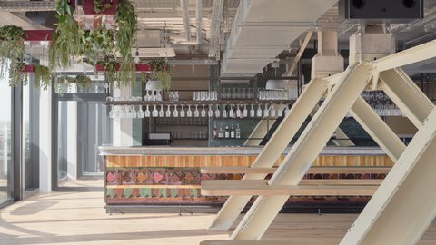 Raum mit einer Bar und weißen Balken. Es hängen bunte Blumen von der Decke