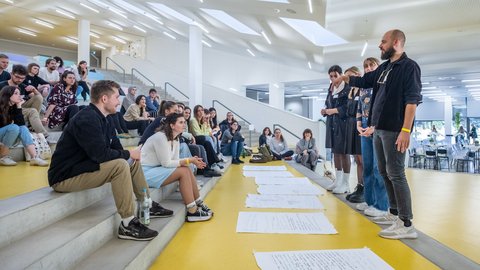 Präsentation von Workshop-Ergebnissen vor Teilnehmenden auf einer Tribüne.