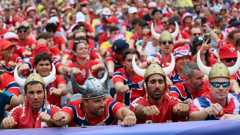 Menschenmenge in roten Fantrikots mit Wikingerhelmen feuert gemeinsam bei einem Public Viewing ihre Mannschaft an.