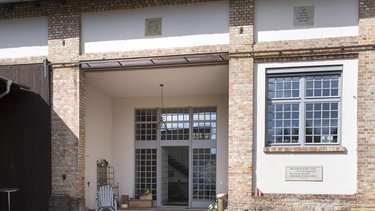 Saniertes Wohnhaus mit Ziegel- und Putzfassade sowie großzügigem Hofeingang.