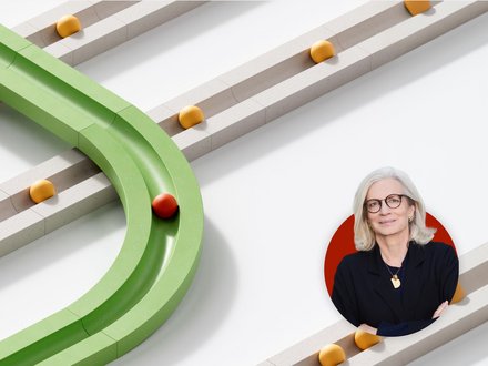 Abstrakte 3D-Grafik mit weißen parallelen Bahnen und gelben Kugeln; eine grüne Spur biegt ab und führt eine rote Kugel. Unten rechts ist ein Porträt einer grauhaarigen Frau mit Brille in einem roten Kreis eingeblendet