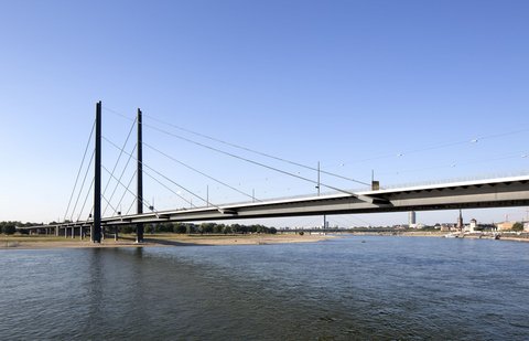 Ausschnitt der Rheinkniebrücke; Im Vordergrund ist der Rhein abgebildet. Im Hintergrund ist das gegenüberliegende Ufer zu sehen. 