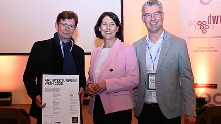 Drei Personen posieren mit Urkunde bei der Verleihung des Architekturpreises Wein 2025.