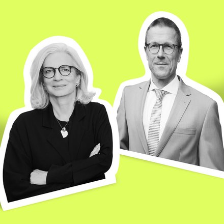 Zwei Personen in Businesskleidung vor einfarbigem Hintergrund, eine mit verschränkten Armen, die andere mit Krawatte