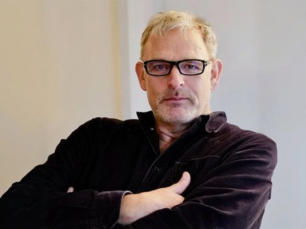 Porträt eines Mannes mit Brille vor einer neutralen Wand