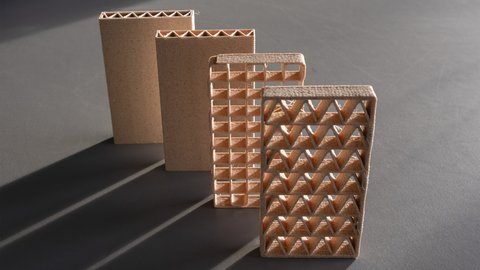 Vier 3D-gedruckte Lehmmodule mit unterschiedlichen inneren Gitterstrukturen stehen auf einer Oberfläche und zeigen verschiedene geometrische Stabilitätsmuster.