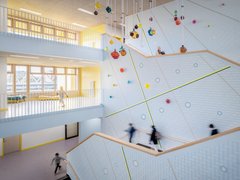 Helles, modernes Treppenhaus mit großen Fenstern, bunten Kugeln an der Decke und mehreren Personen auf den Treppen und im Gang