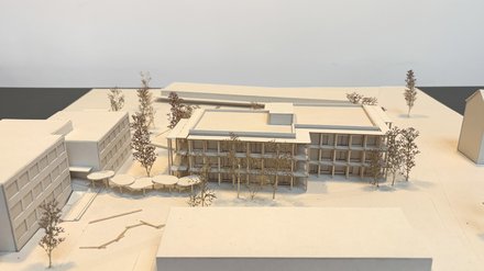 Architekturmodell eines mehrgeschossigen Schulgebäudes mit umlaufendem Laubengang und Bäumen.