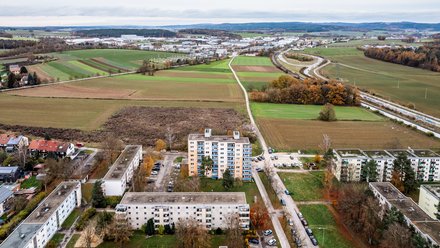 Luftaufnahme eines Wohngebiets am Stadtrand mit Feldern und Straßen.