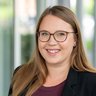 Porträt einer Frau mit Brille in Innenraum Freundlich lächelnde Frau im Business-Outfit vor hellem Hintergrund.