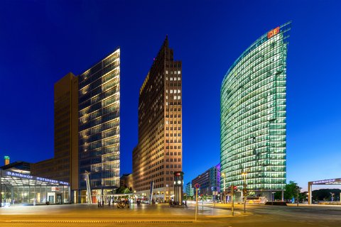 „Der Potsdamer Platz in Berlin zur Blauen Stunde mit den markanten, hell erleuchteten Hochhäusern unter einem tiefblauen Abendhimmel.“