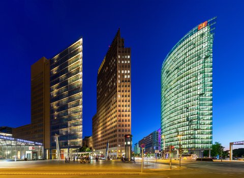 „Der Potsdamer Platz in Berlin zur Blauen Stunde mit den markanten, hell erleuchteten Hochhäusern unter einem tiefblauen Abendhimmel.“