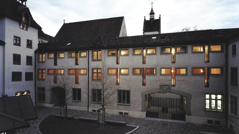 Historische Gebäudefassade bei Nacht mit beleuchteten Fenstern.