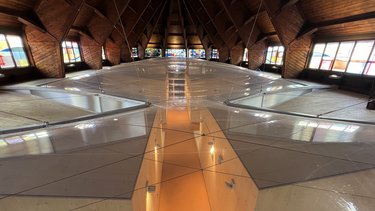 Innenansicht eines Dachraums mit Holzbalken und begehbarem Glasboden.