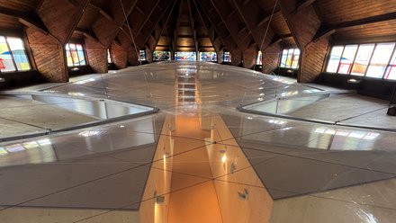 Innenansicht eines Dachraums mit Holzbalken und begehbarem Glasboden.