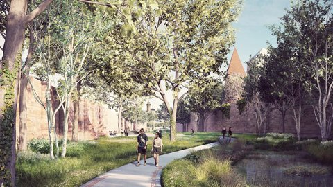 Schmaler gepflasterter Fußweg mit rotem Ziegelbelag entlang eines flachen Wasserlaufs. Hohe Bäume säumen beide Seiten. Paare joggen/gehen auf dem Weg. Historische Steinmauern und Gebäudetürme sichtbar. Grüne Vegetation und Wiese.