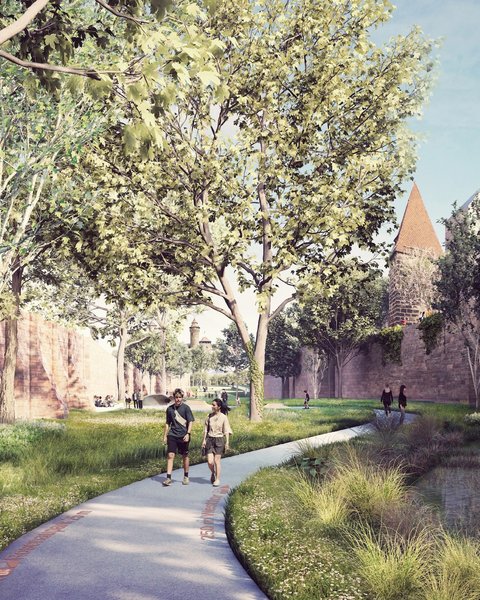 Schmaler gepflasterter Fußweg mit rotem Ziegelbelag entlang eines flachen Wasserlaufs. Hohe Bäume säumen beide Seiten. Paare joggen/gehen auf dem Weg. Historische Steinmauern und Gebäudetürme sichtbar. Grüne Vegetation und Wiese.