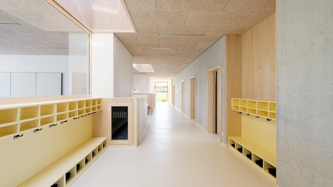 Heller Flur mit Garderobenbänken und Haken an beiden Seiten in einem modernen Kinderhaus