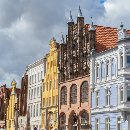 Historische, farbenfrohe Giebelhäuser in einer norddeutschen Altstadt unter bewölktem Himmel.