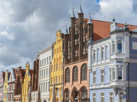 Historische, farbenfrohe Giebelhäuser in einer norddeutschen Altstadt unter bewölktem Himmel.