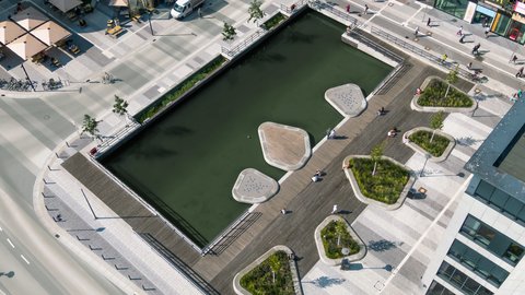 Luftaufnahme des Holstenfleets in Kiel mit Wasserfläche, bepflanzten Inseln und neu gestalteten Platz- und Aufenthaltsflächen zwischen den umliegenden Gebäuden.