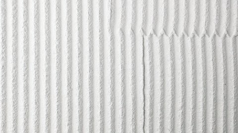 Helle Putzoberfläche mit parallelen, tiefen Rillen; Stoßfuge mit kleinen Zähnen in der Mitte.