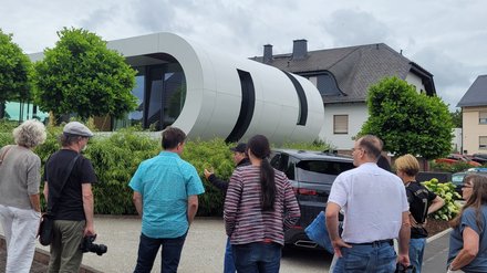 Außenansicht des Curved House; Betrachter stehen vor dem Curved House