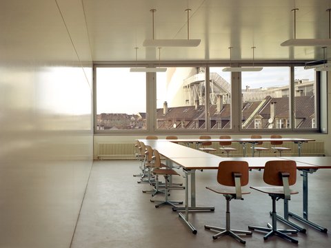 Heller Innenraum mit Arbeitsplätzen und großen Fenstern mit Blick auf die Stadt.