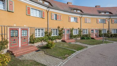 Wohnanlage mit farbiger Putzfassade und Reihenhäusern.