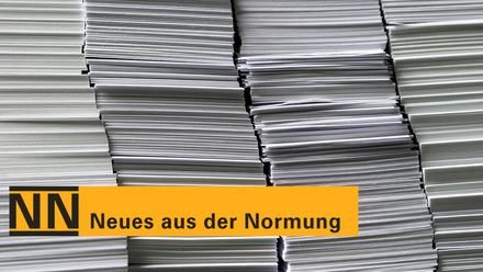 Hohe Stapel weißer Papierbögen; darüber ein gelber Balken mit der Aufschrift „NN – Neues aus der Normung“
