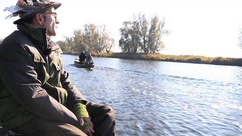 Zwei Personen in Outdoor-Kleidung sitzen in Booten auf einem Fluss, im Hintergrund Bäume und Ufervegetation