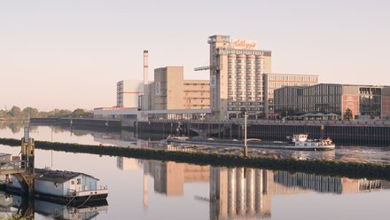 Außenansicht des ehemaligen Kellogg’s-Getreidesilos an einem Fluss mit Schiffen