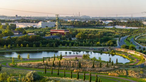 Landschaftspark mit Teich, Wegen, Grünflächen und einem Spielplatz.