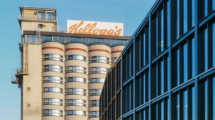 Hochhaus mit abgerundeten Balkonen und einem großen, orangefarbenen "Kellogg's"-Schriftzug auf dem Dach.