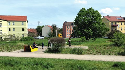 Naturnahe Grünanlage mit Sitzgelegenheiten und Wegen zwischen Wohnhäusern.