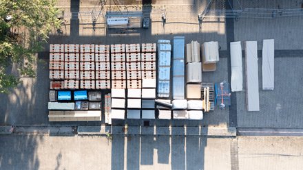 Luftaufnahme von ordentlich gestapelten Baumaterialien auf einem Hof.