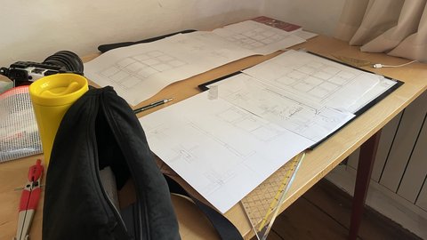 Schreibtisch mit Architektur Skizzen einem Zirkel und einem Geodreieck