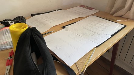 Schreibtisch mit Architektur Skizzen einem Zirkel und einem Geodreieck