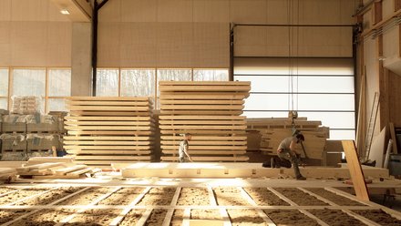 Ein großer Industriebereich mit Arbeitern, die Holzbohlen und -planken zusammenbauen.