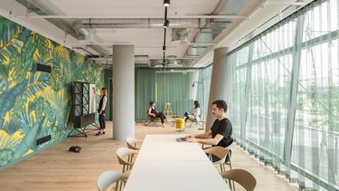 Langer Raum mit Arbeitsplätzen, Sitzbänken und Blick nach außen.