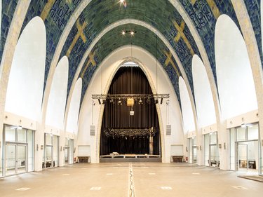 Großer Kirchenraum mit hohen Gewölben, Fliesenmosaik und einer Bühne im Hintergrund.