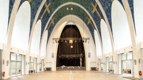 Großer Kirchenraum mit hohen Gewölben, Fliesenmosaik und einer Bühne im Hintergrund.
