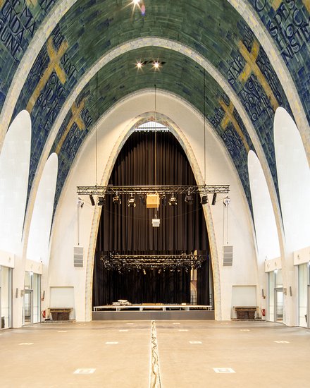 Großer Kirchenraum mit hohen Gewölben, Fliesenmosaik und einer Bühne im Hintergrund.