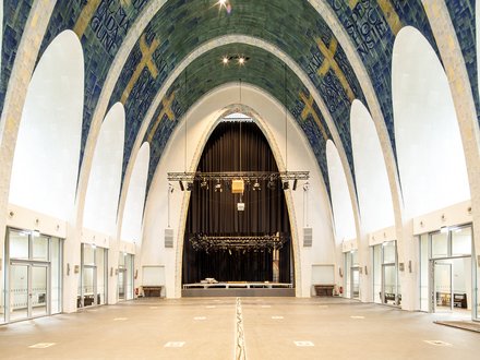 Großer Kirchenraum mit hohen Gewölben, Fliesenmosaik und einer Bühne im Hintergrund.