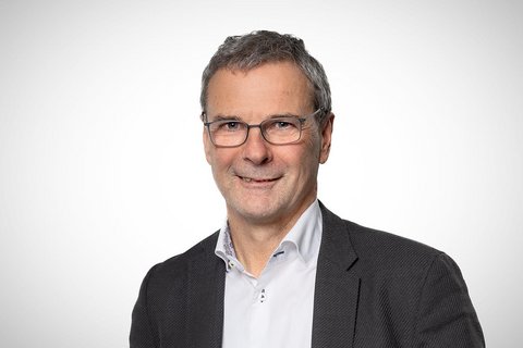 Porträt eines Mannes mit Brille vor neutralem Hintergrund